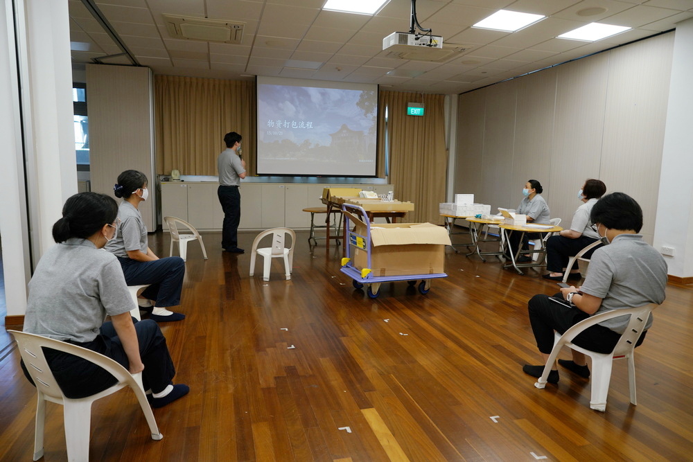 Staff undergoing a briefing before packing the care packs. (Photo by Chan May Ching)